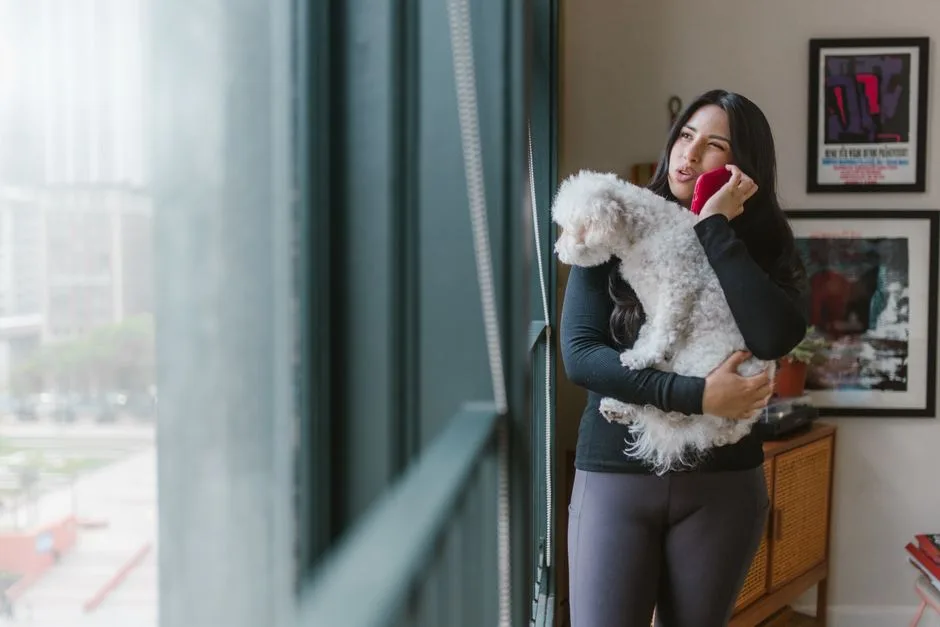 Woman making a phone call to a landlord about a pet-friendly apartment, looking confident