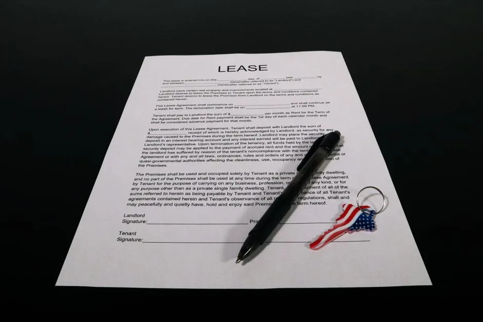 Person signing a rental lease agreement with pen and calculator