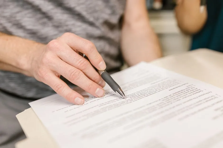 Person carefully reading through a rental lease agreement with a cat sitting on the table nearby